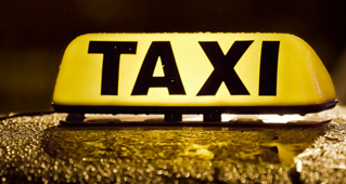 Yellow Taxi sign on top of a vehicle